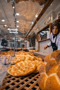 A bakery showcasing freshly baked bread with a staff member in view. Warm, inviting ambiance.