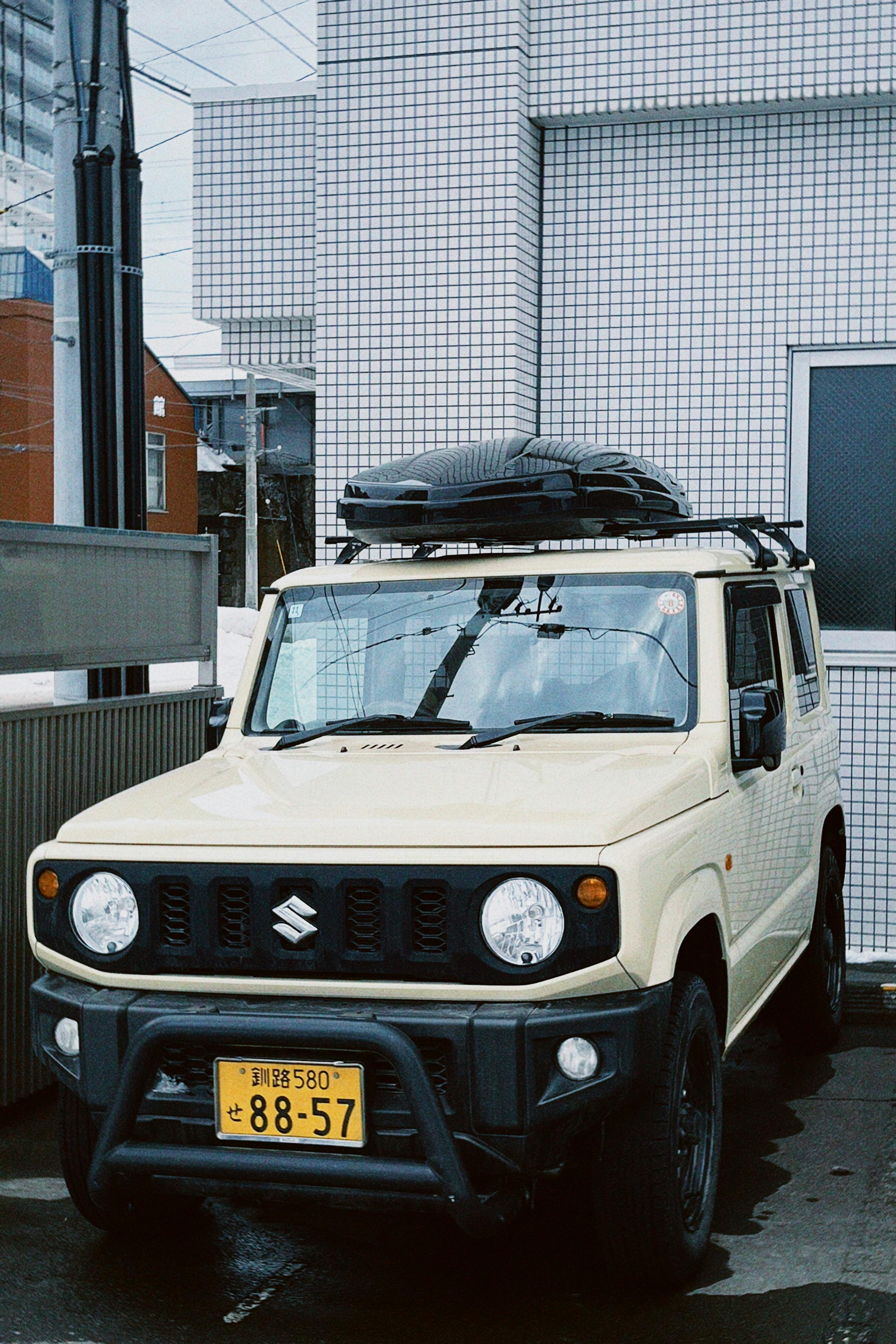 Kostenlos Ein beigefarbener Geländewagen mit Dachbox parkt im Freien auf einer Straße in Sapporo, Japan. Stock-Foto