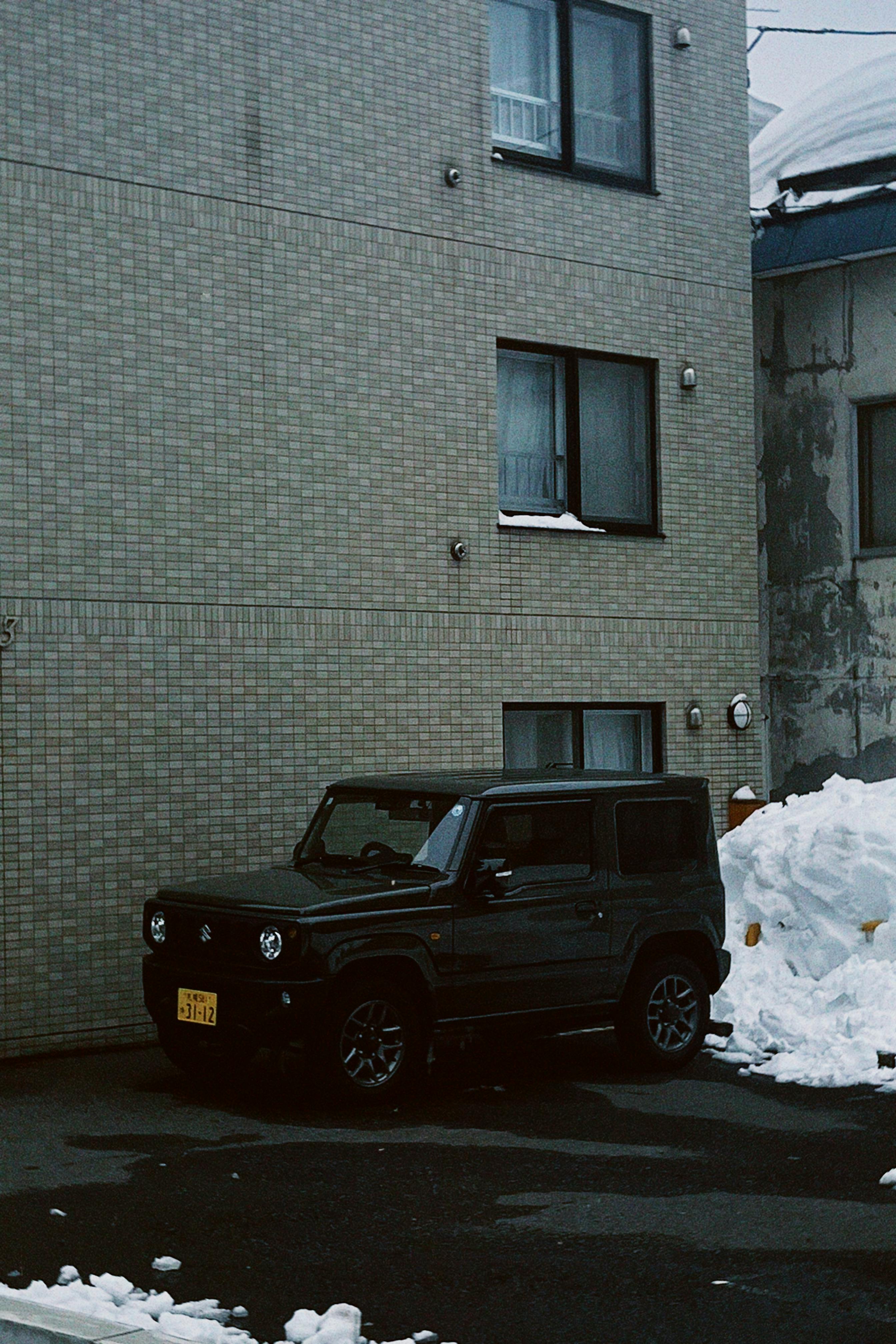 gratis Een auto geparkeerd voor een gebouw in het besneeuwde Sapporo, Hokkaido, Japan, die de serene stedelijke schoonheid van de winter vastlegt. Stockfoto