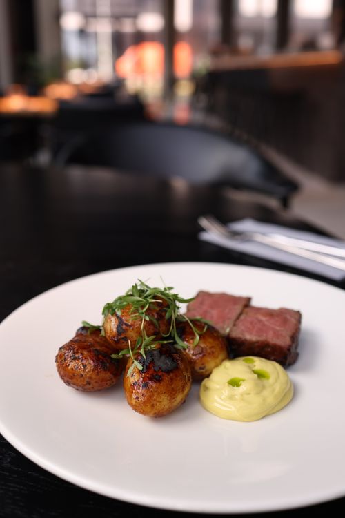 Free Elegant steak dinner with roasted potatoes and a dollop of creamy sauce, perfect for fine dining. Stock Photo