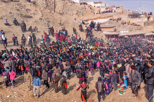 A vibrant gathering of people celebrating at a festival in Huangnan, Qinghai Province, China.