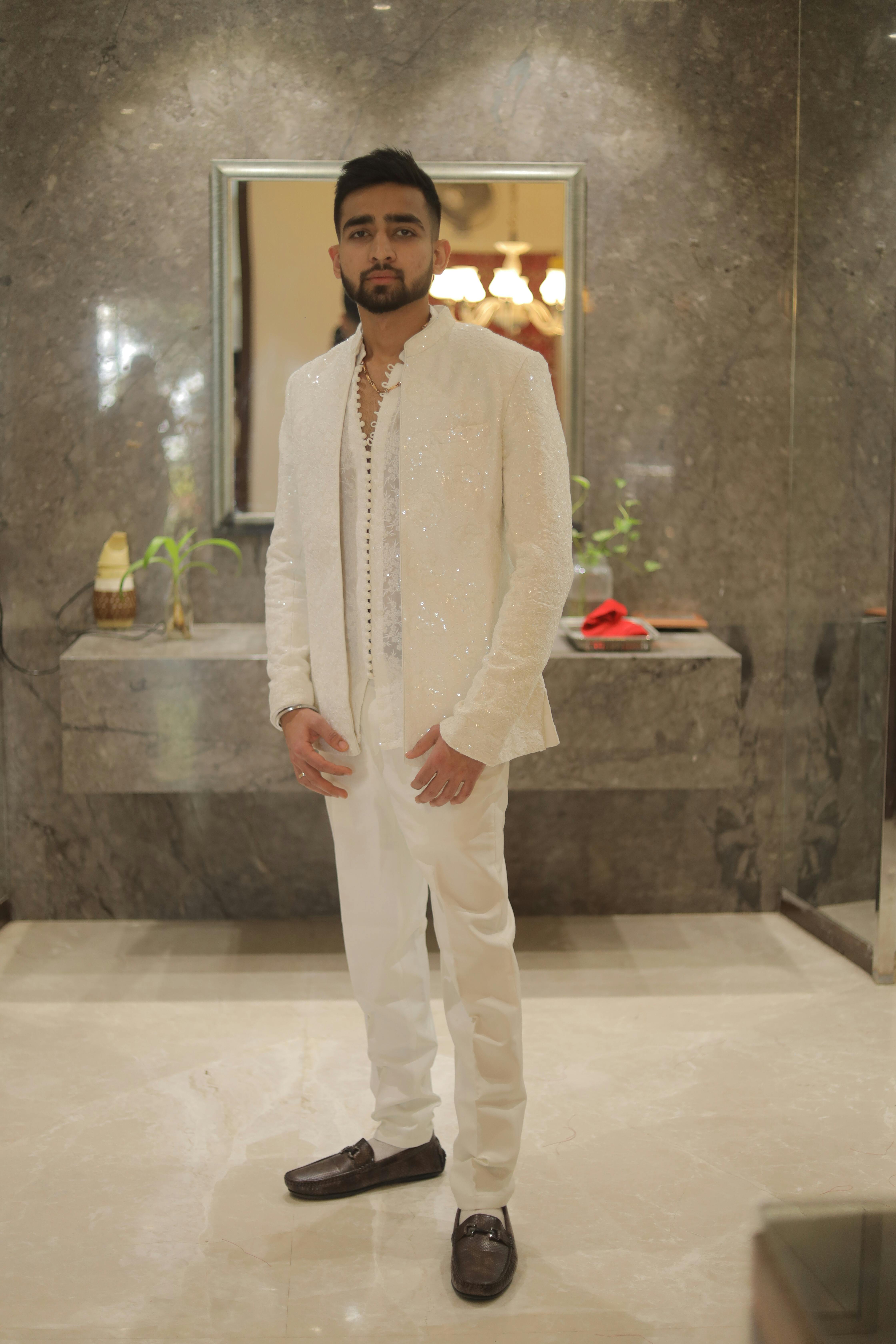Portrait of a man in wedding attire standing indoors, exuding elegance and charm.