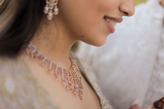 A close-up of a bride's joyful smile and elegant jewelry, highlighting traditional wedding accessories.