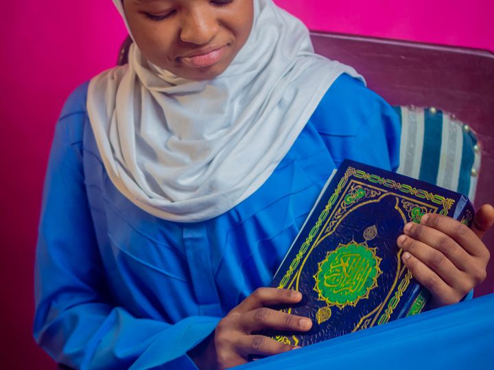 Young Muslim woman in headscarf holding the Quran