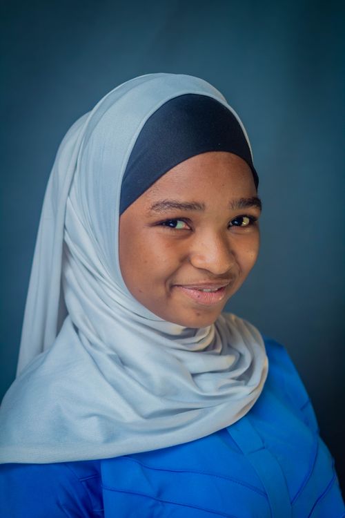 Free A bright portrait of a young girl wearing a hijab, exuding warmth and confidence. Stock Photo