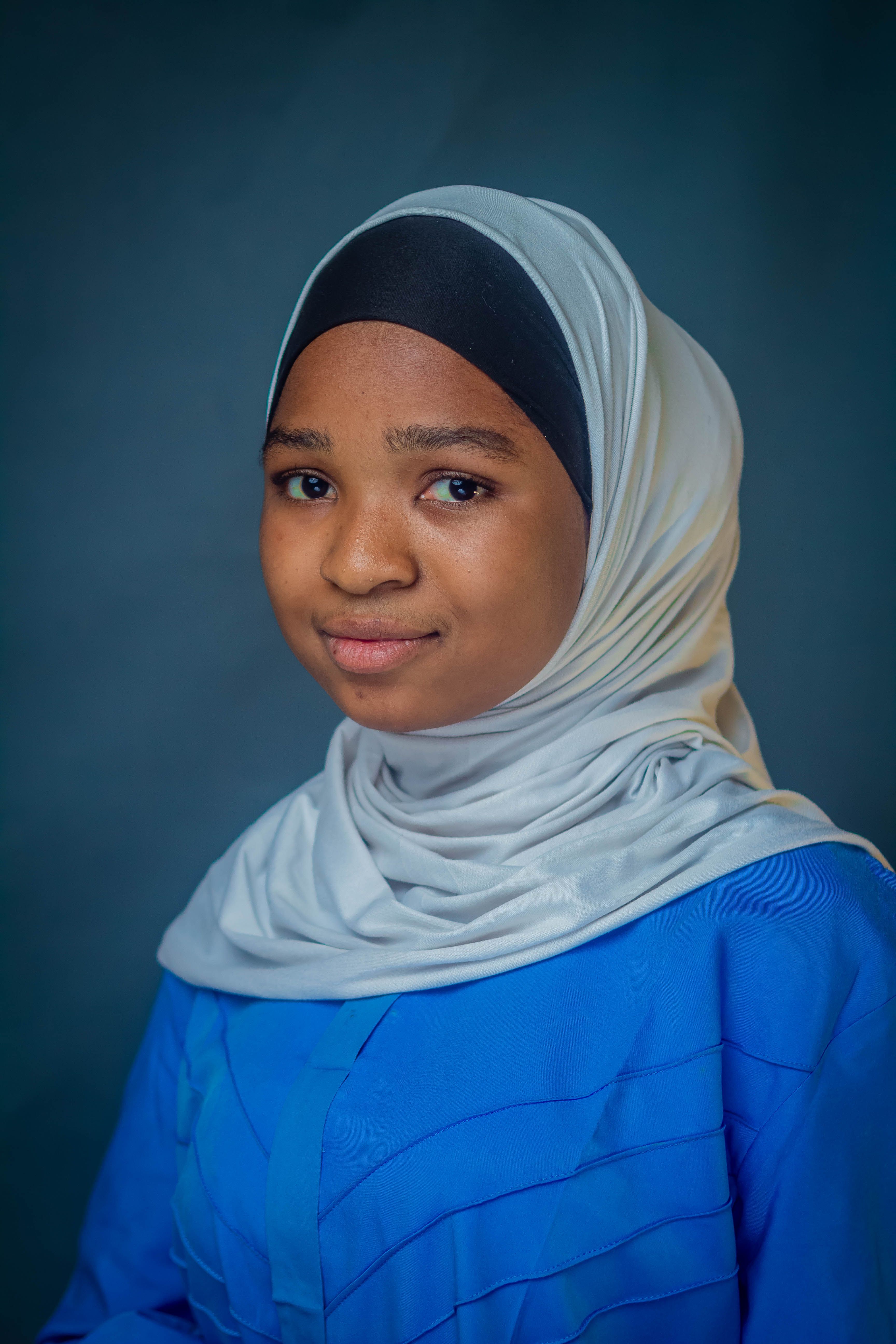 Elegant portrait of a young woman wearing a hijab and a blue top.