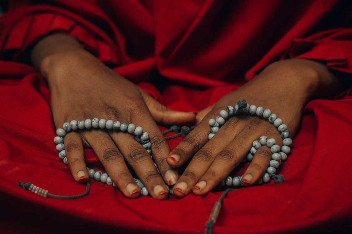 Close-up of Hands with Prayer Beads on Red Fabric · Free Stock Photo