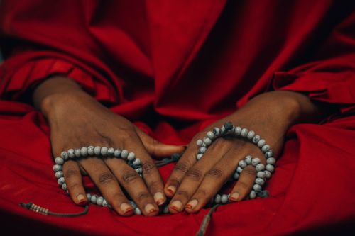 Free Close-up of hands with prayer beads on vibrant red cloth, depicting tranquility and spirituality. Stock Photo