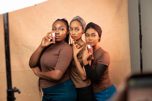 Free Three women showcasing makeup products in a professional studio environment. Stock Photo