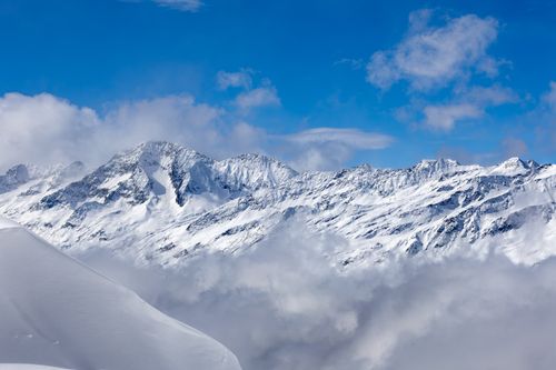 Free Snow-covered mountains with blue sky and clouds in Korutany, Austria. Stock Photo