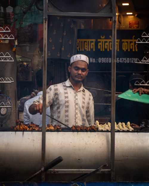Free A street vendor grills skewers in a bustling market, showcasing vibrant street food culture. Stock Photo