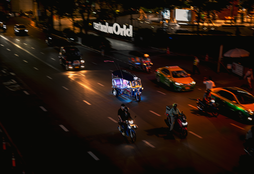 Motorcycles and vehicles on a bustling city street at night in urban Kuwait.