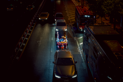 Aerial view of a busy street in Kuwait City at night with cars and buses.