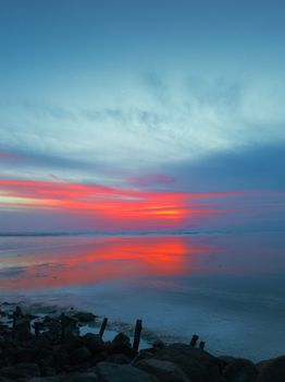Stunning sunset over Tanjung Bungah beach in Penang with vivid red and blue skies reflecting on the water.