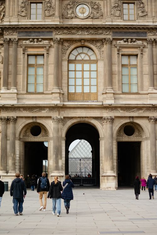 Free People walking towards the Louvre Museum entrance with its iconic architecture in Paris, France. Stock Photo