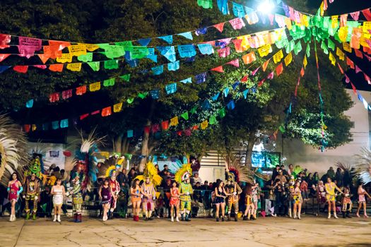 Lively traditional festival with vibrant costumes and decorations captured at night outdoors.