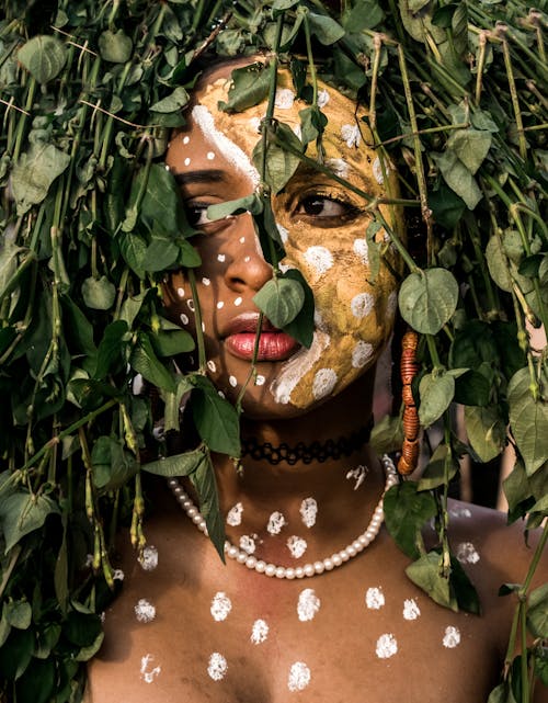 Person Mit Gesichtsfarbe Hinter Den Blättern Einer Pflanze
