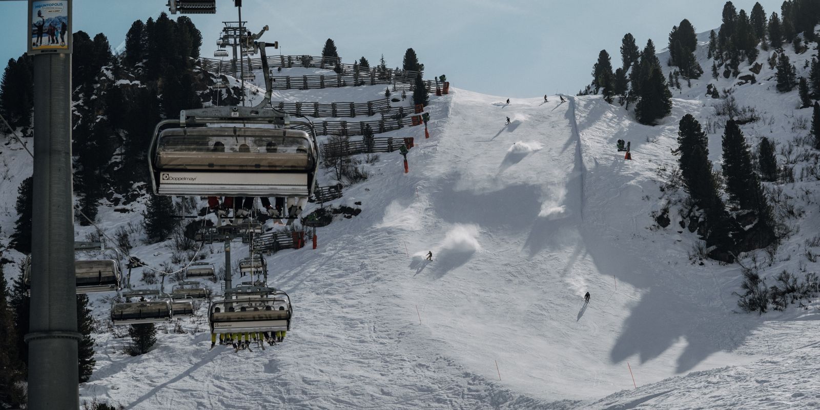 A snowy ski slope with a chairlift climbing through the mountains