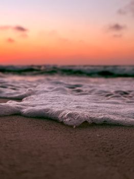 Gentle waves on a sandy beach during a vibrant sunset in Alexandria, Egypt.