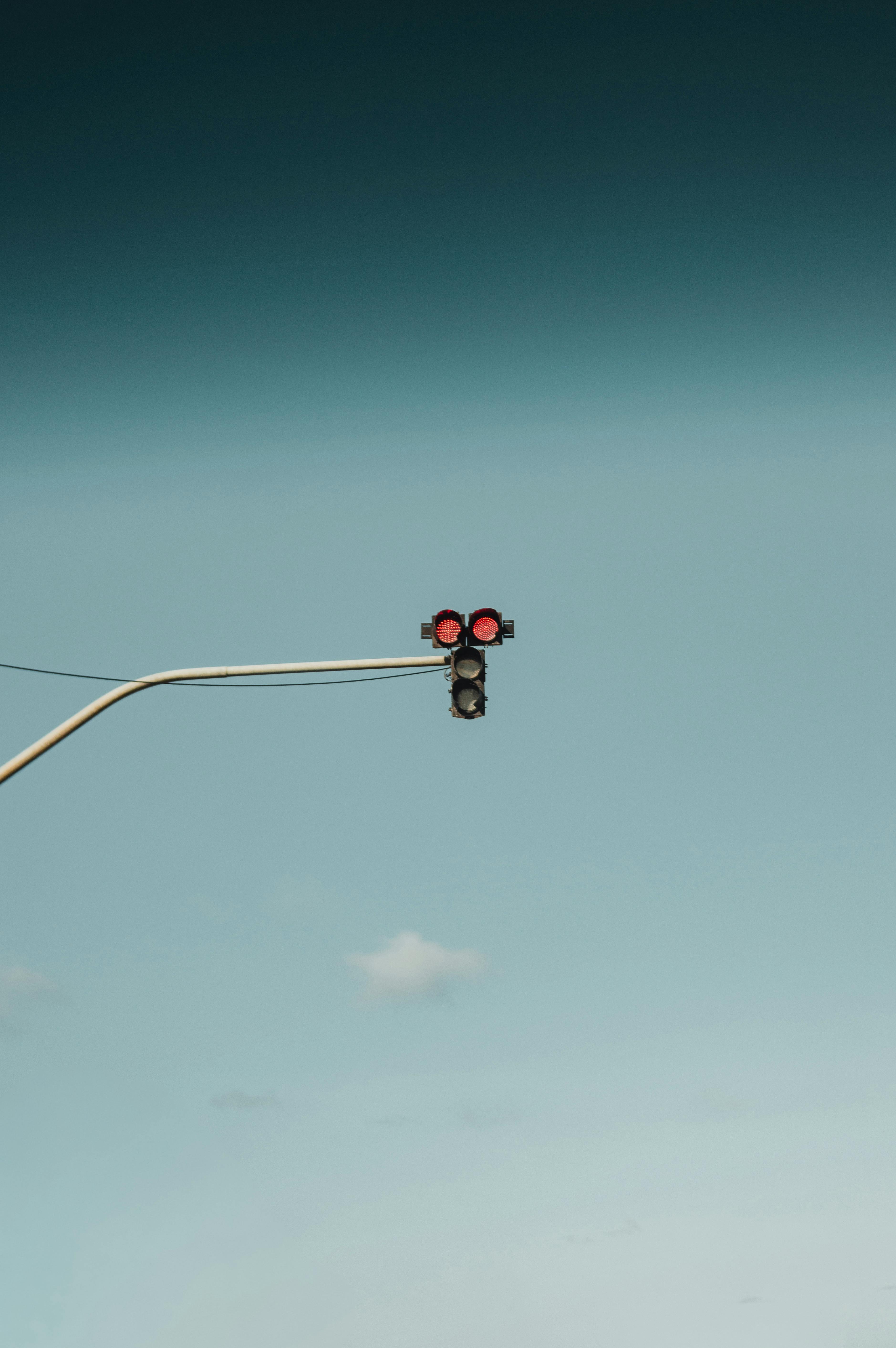 Gratis Una fotografía minimalista de un semáforo que muestra luces rojas contra un cielo azul claro. Foto de stock