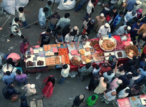 A bustling street food market scene from above in Dhaka, showcasing diverse South Asian cuisine.