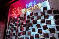 这家复古照片店设有霓虹灯招牌，提供30分钟拍照服务，店内四周悬挂着宝丽来相机