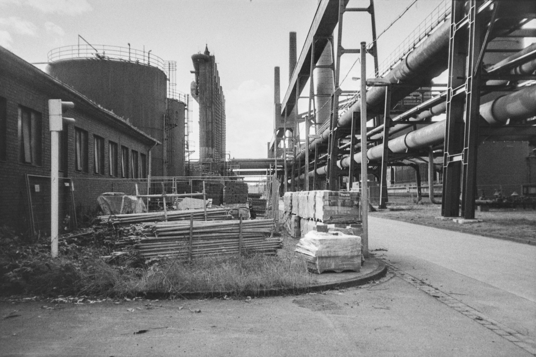 Black and white photo of an industrial factory complex with pipelines and storage tanks.