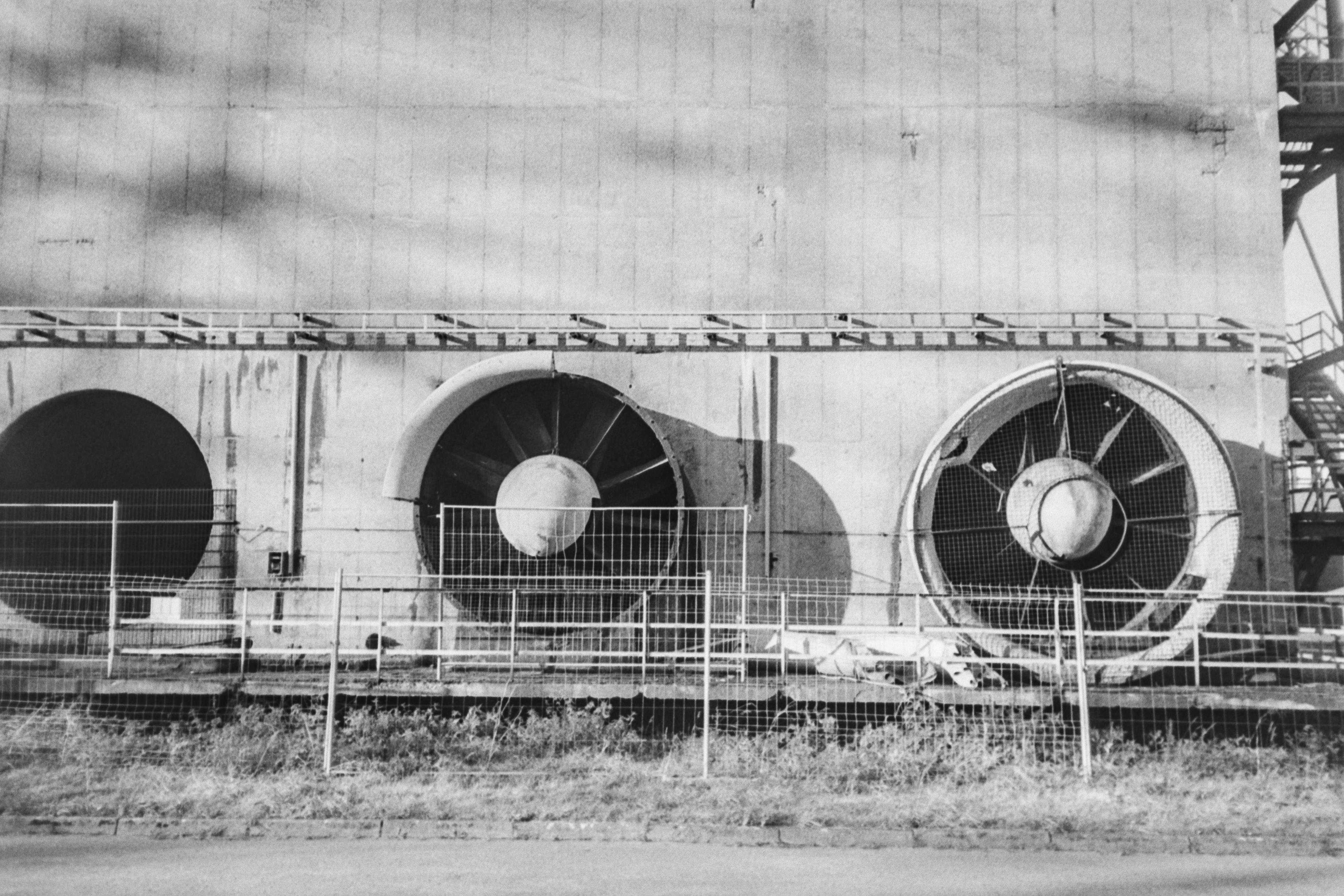 Ücretsiz Çit arkasında bulunan büyük endüstriyel soğutma fanlarının siyah beyaz fotoğrafı. Stok Fotoğraflar