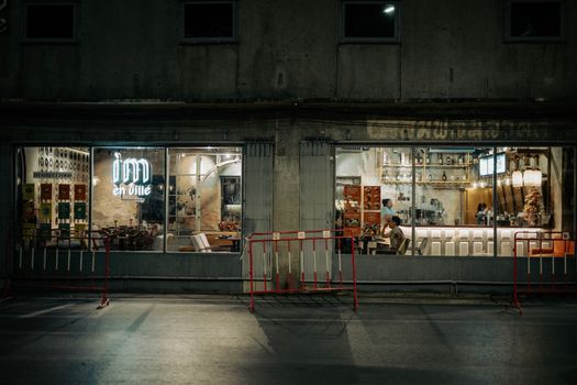 A nighttime glance at a cafe with ambient lighting and a neon sign, inviting a warm indoor atmosphere.