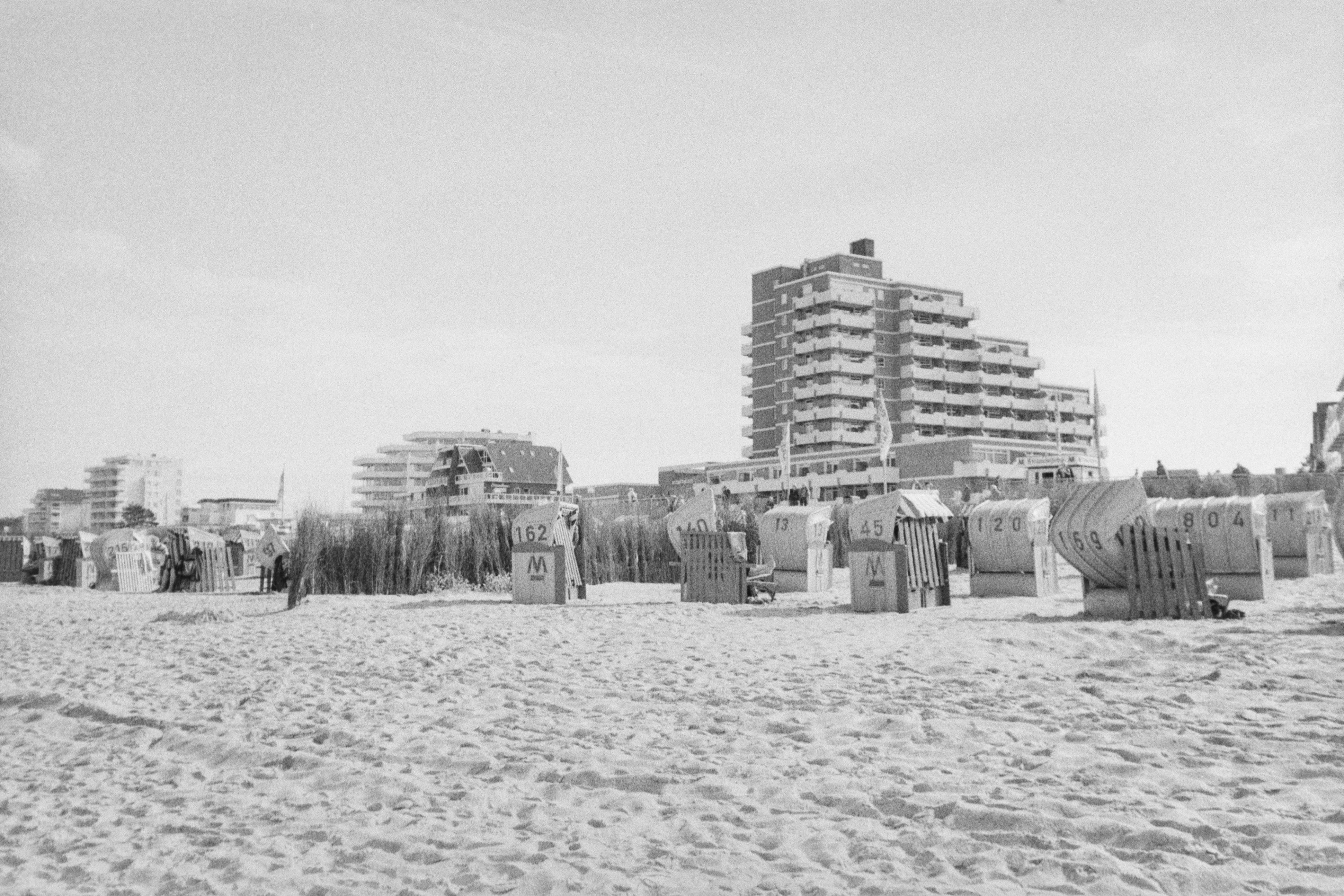 De franc Una vista panoràmica de la platja amb cadires tradicionals de Strandkorb i edificis moderns en un entorn costaner. Foto d'estoc