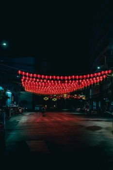 Red lanterns light up a peaceful street at night, creating a vivid and festive atmosphere.