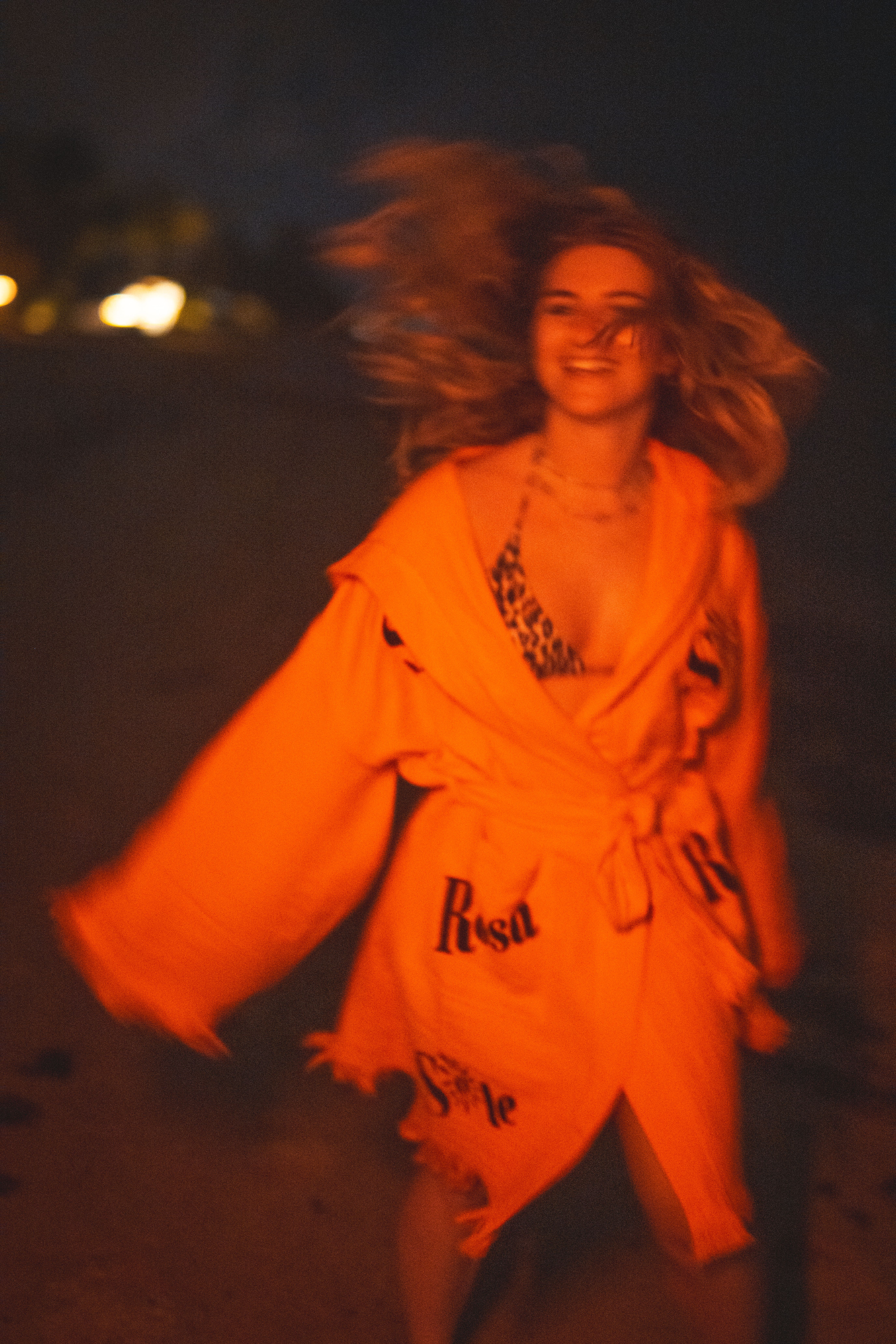 Happy woman in orange robe at night on beach · Free Stock Photo