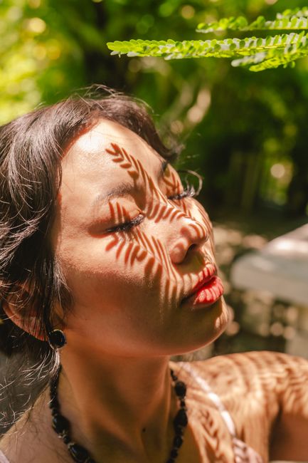 Beautiful artistic portrait of a woman with leaf shadows outdoors, creating a natural aesthetic.