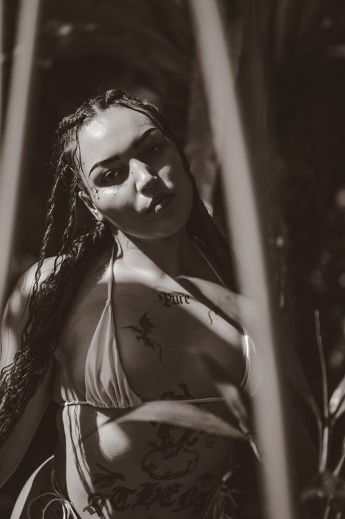 Free Moody sepia portrait of a woman with tattoos amidst nature, styled with braided hair. Stock Photo