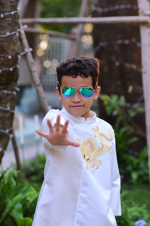 Free A confident child poses with sunglasses in an elegant outfit outdoors. Stock Photo