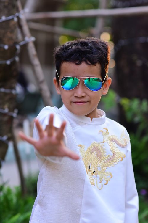 Free Child wearing reflective sunglasses, posing confidently in an outdoor setting. Stock Photo