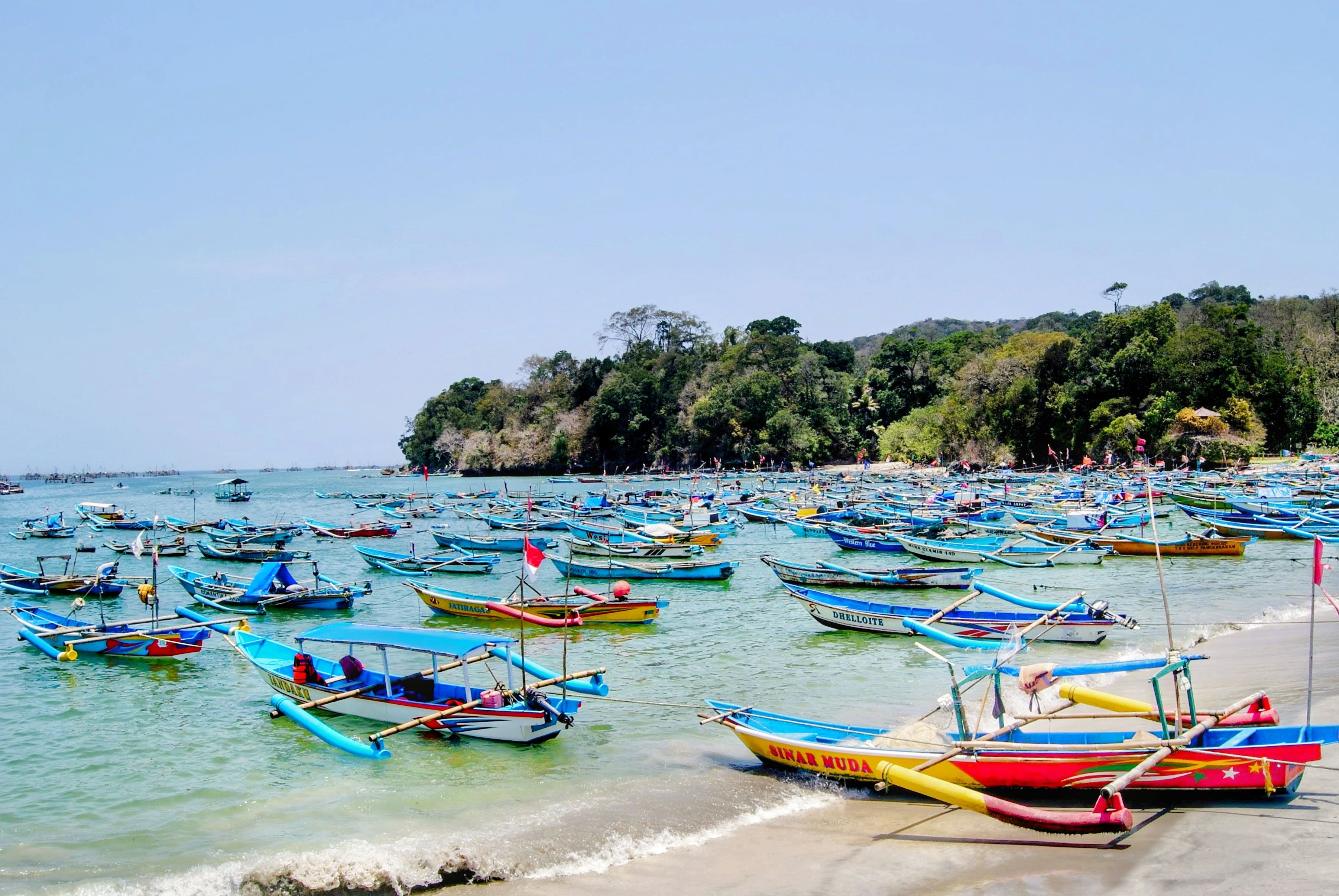 Fotomural Coloridos barcos tradicionales anclados frente a la costa de Pangandaran, Indonesia, que muestran la cultura pesquera local.