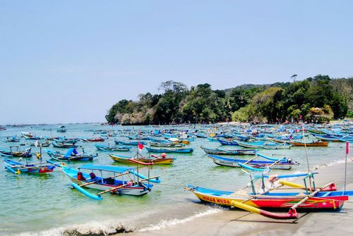 Free Colorful traditional boats anchored off the coast of Pangandaran, Indonesia, showcasing local fishing culture. Stock Photo