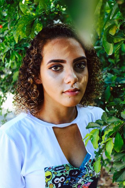A young woman poses in a vibrant green garden, emphasizing natural beauty and fashion.