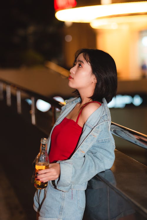 Woman Wearing Blue Denim Jacket While Holding Bottle