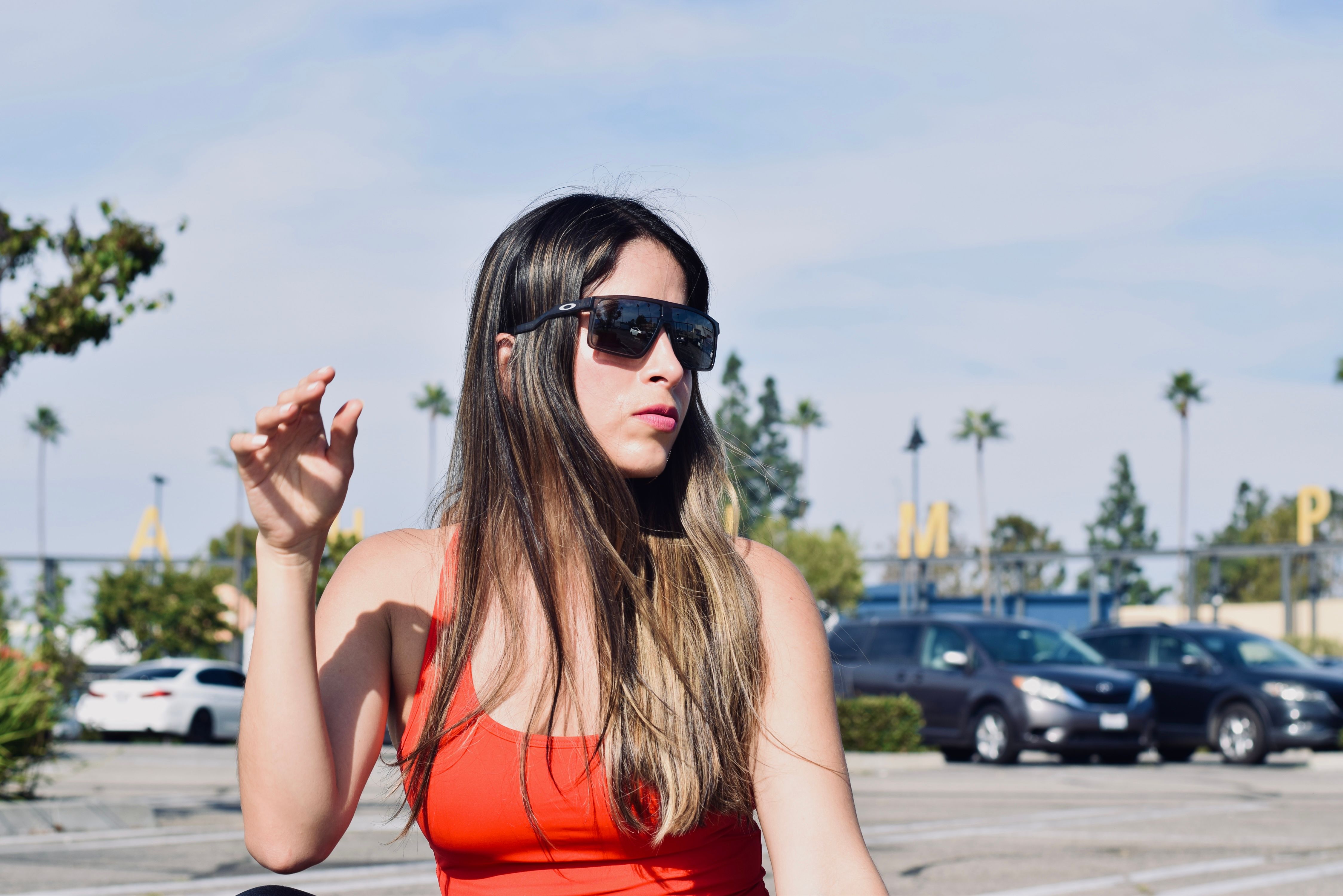Stylish woman in sunglasses at a parking lot in Anaheim, California on a sunny day.