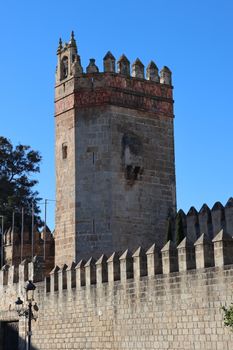 Old stone castle tower with crenellations in Andalucía, Spain, under clear blue skies.