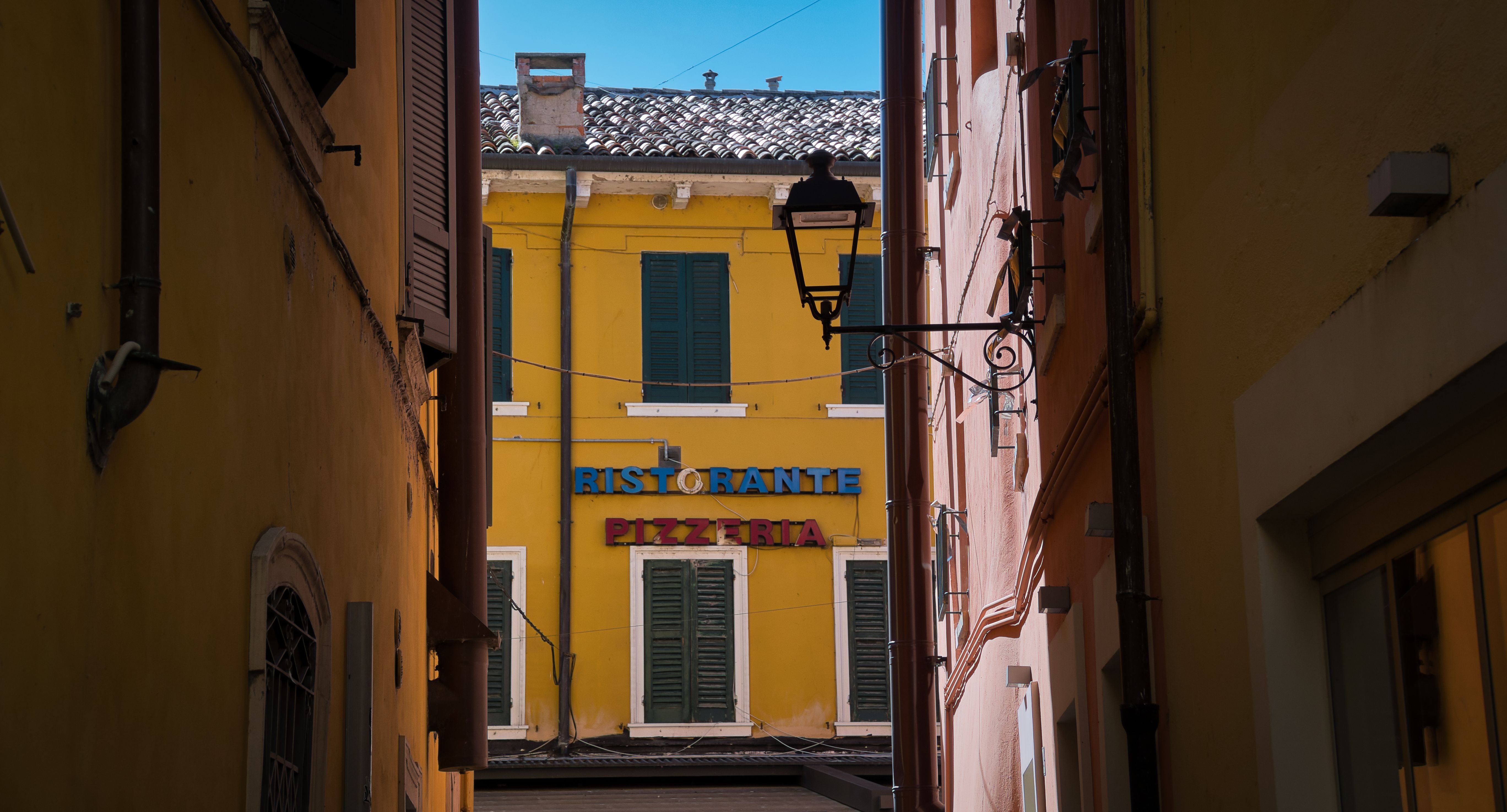 A vibrant alleyway view leading to a restaurant in Peschiera del Garda, Italy.