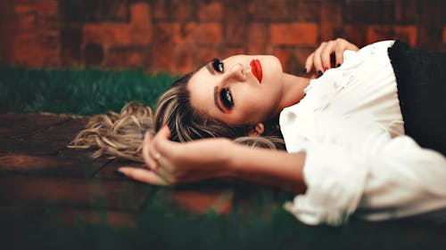 Woman Lying Down While Wearing White Top