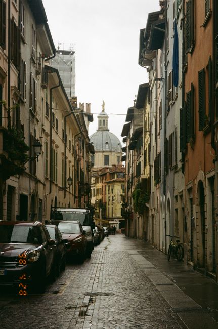 Picturesque street view in Verona, Italy, featuring cobblestone path and dome.