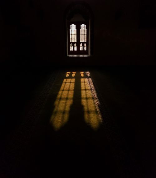 Free A dramatic play of light and shadow from an ornate mosque window creates a serene scene. Stock Photo