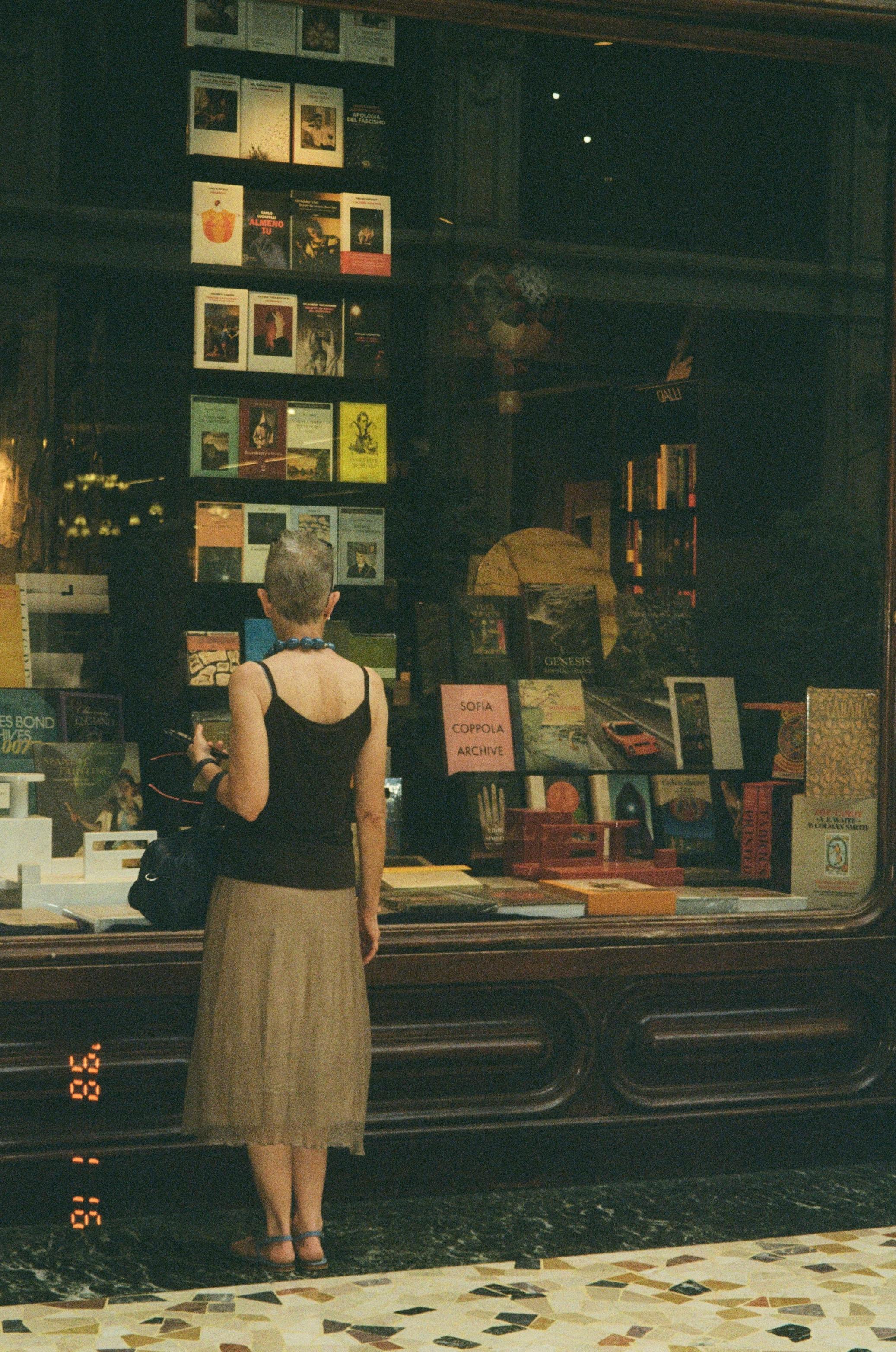 無料 書店で、女性がショーウィンドウに並べられた様々な本を眺めている。 写真素材