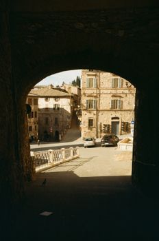 View of a picturesque Italian village through a stone archway, capturing rustic charm.