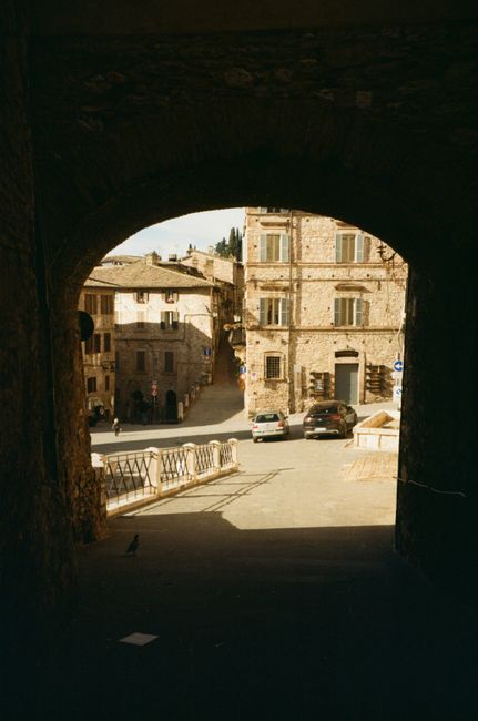 View of a picturesque Italian village through a stone archway, capturing rustic charm.