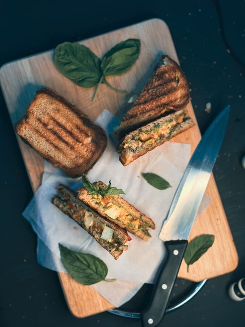 Free Top view of grilled vegetable sandwiches with basil on a cutting board, showcasing fresh ingredients. Stock Photo
